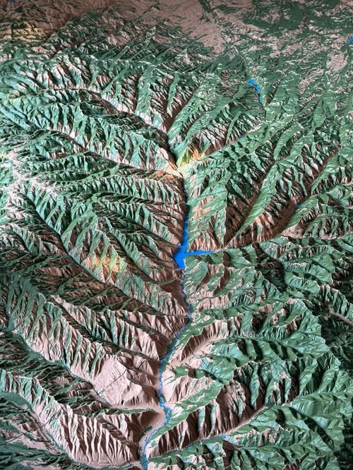 Multicolor terrain model with green vegetation, tan exposed land, and blue water